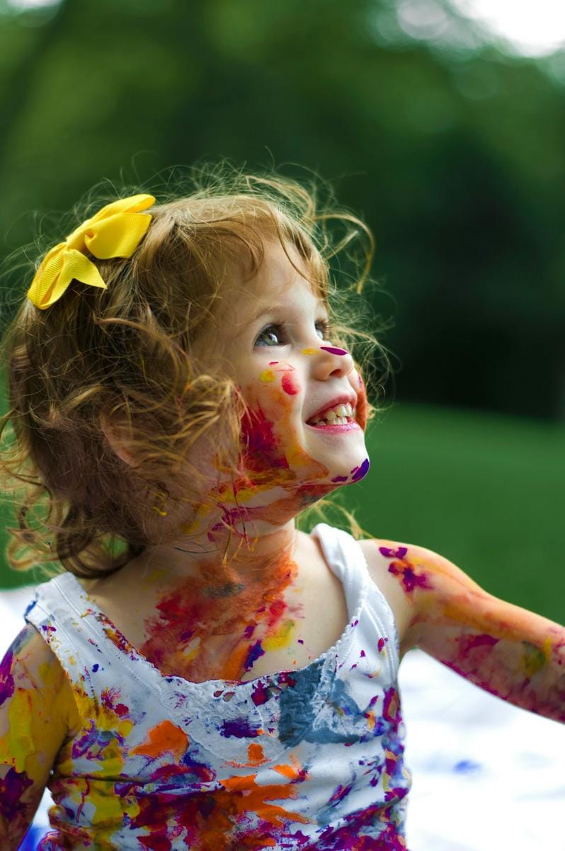 Close-up of a toddler wearing a humorous graphic tee with a witty slogan, smiling in a sunny park